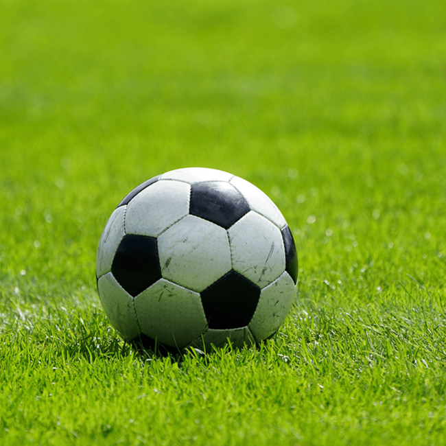 Ein klassischer schwarz-weißer Fußball liegt auf einer Rasenfläche.